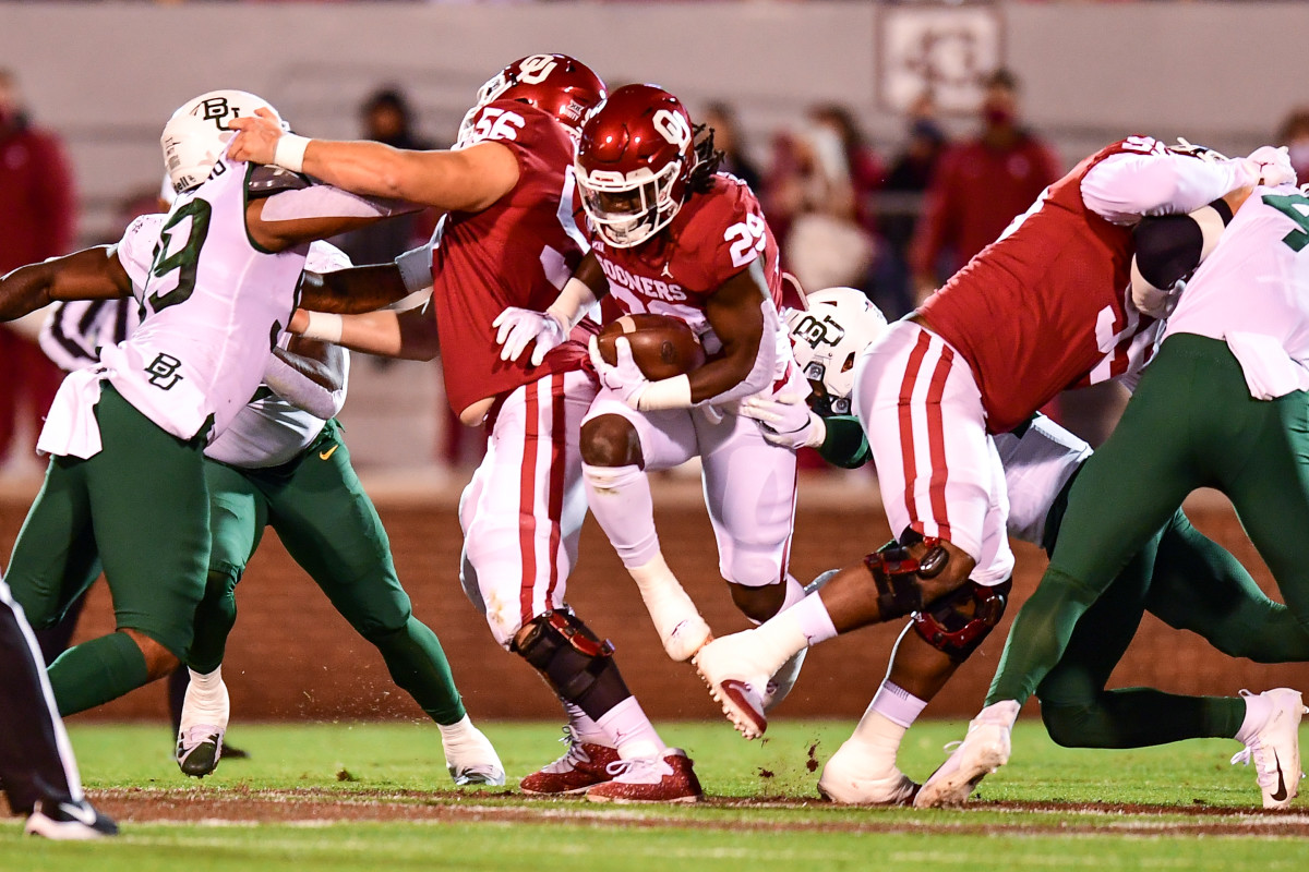 Rhamondre Stevenson (29) looks for running room behind a block from Creed Humphrey (56).